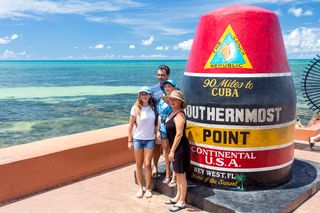 A family posing next to the southernmost point on Whitehead Street.