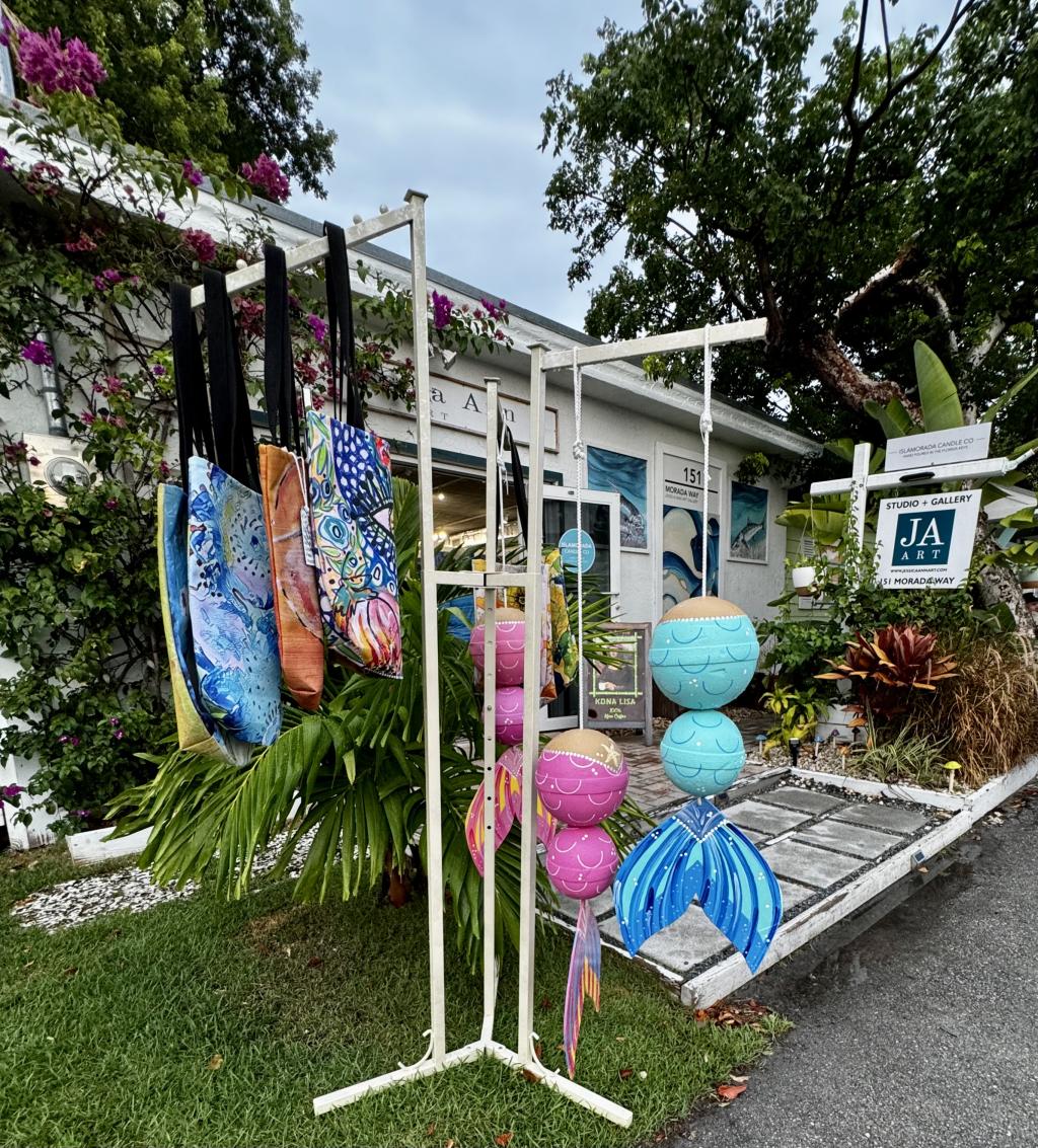 Colorful art and tote bags outside a gallery at Morada Way's Art Walk.