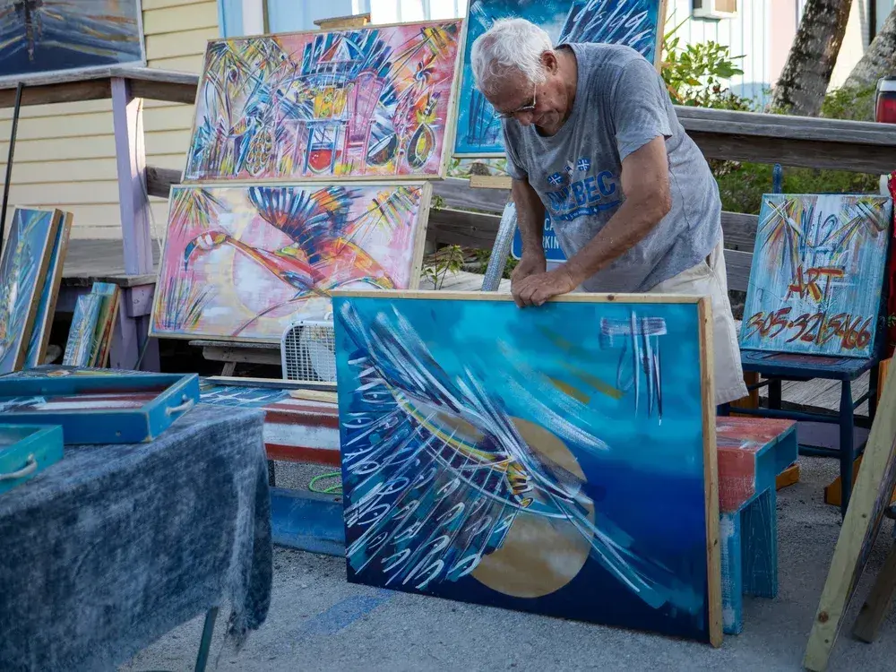 Artist displaying vibrant abstract paintings outdoors.