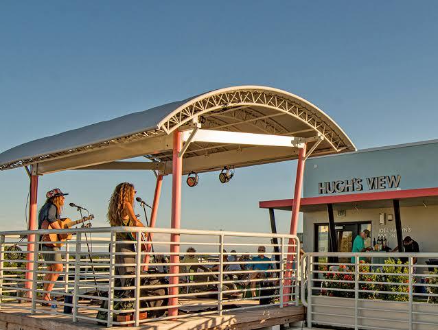 Musicians performing on a rooftop under a canopy at sunset.