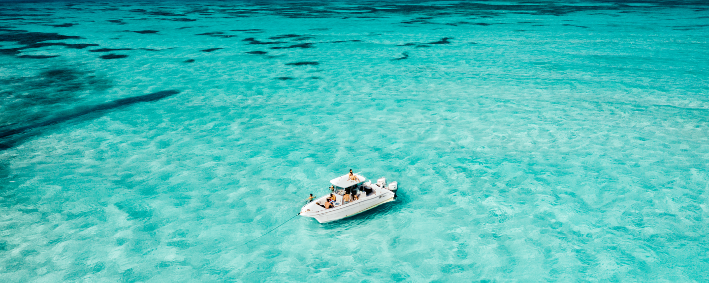 Boat floating on clear turquoise water, viewed from above.