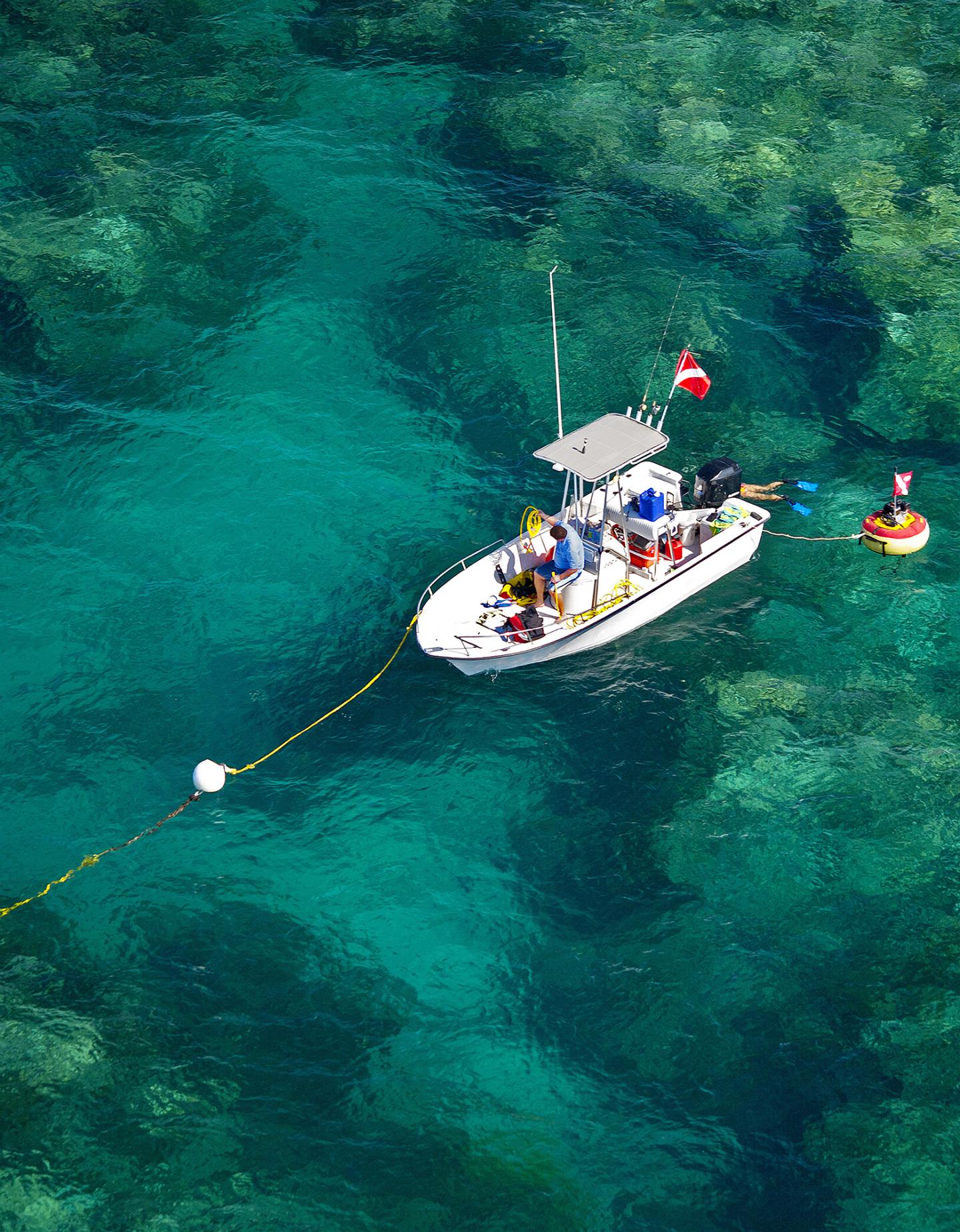 Boat over clear turquoise water with diving gear on board.