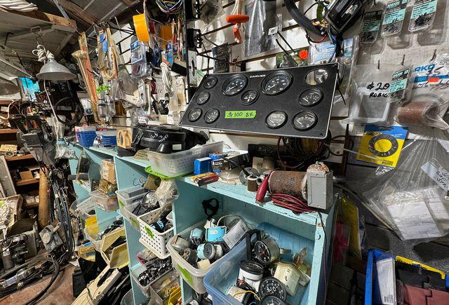 Cluttered workshop with tools and parts on shelves and walls.