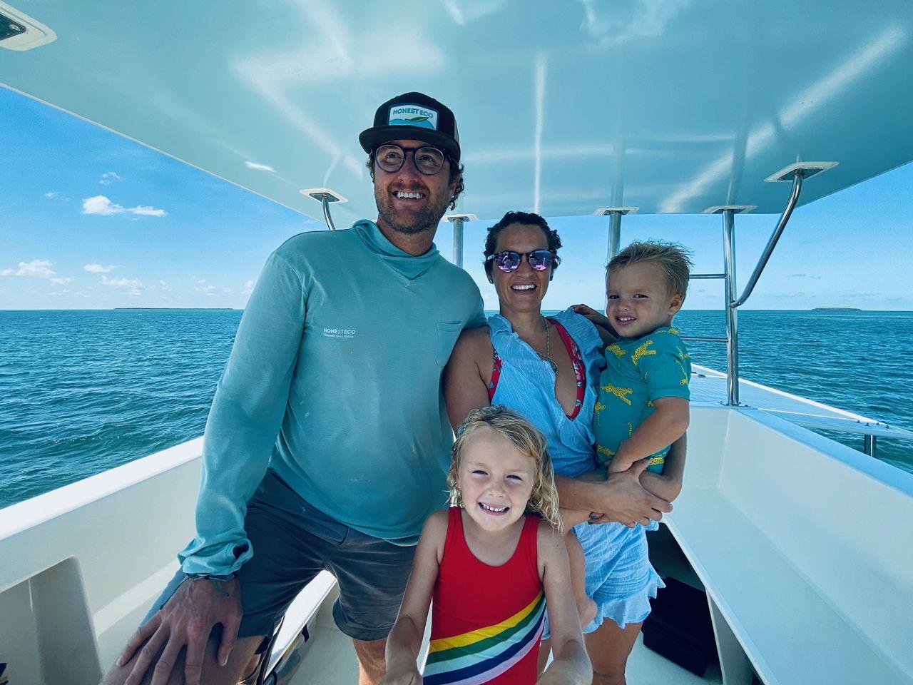 Family smiling on a boat under a clear blue sky.