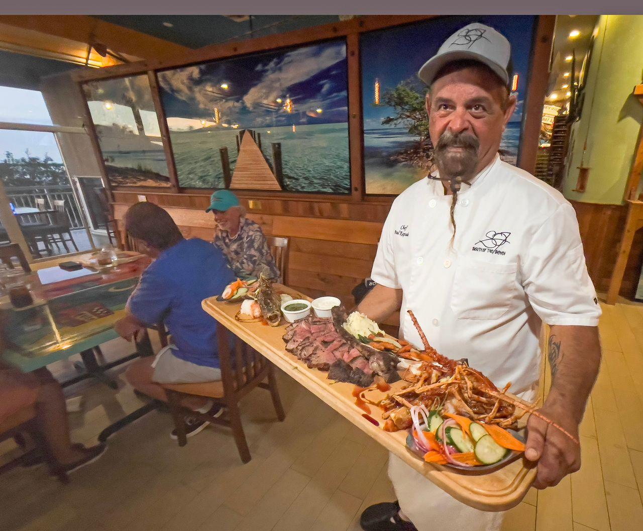 Chef presenting a seafood platter in a restaurant.
