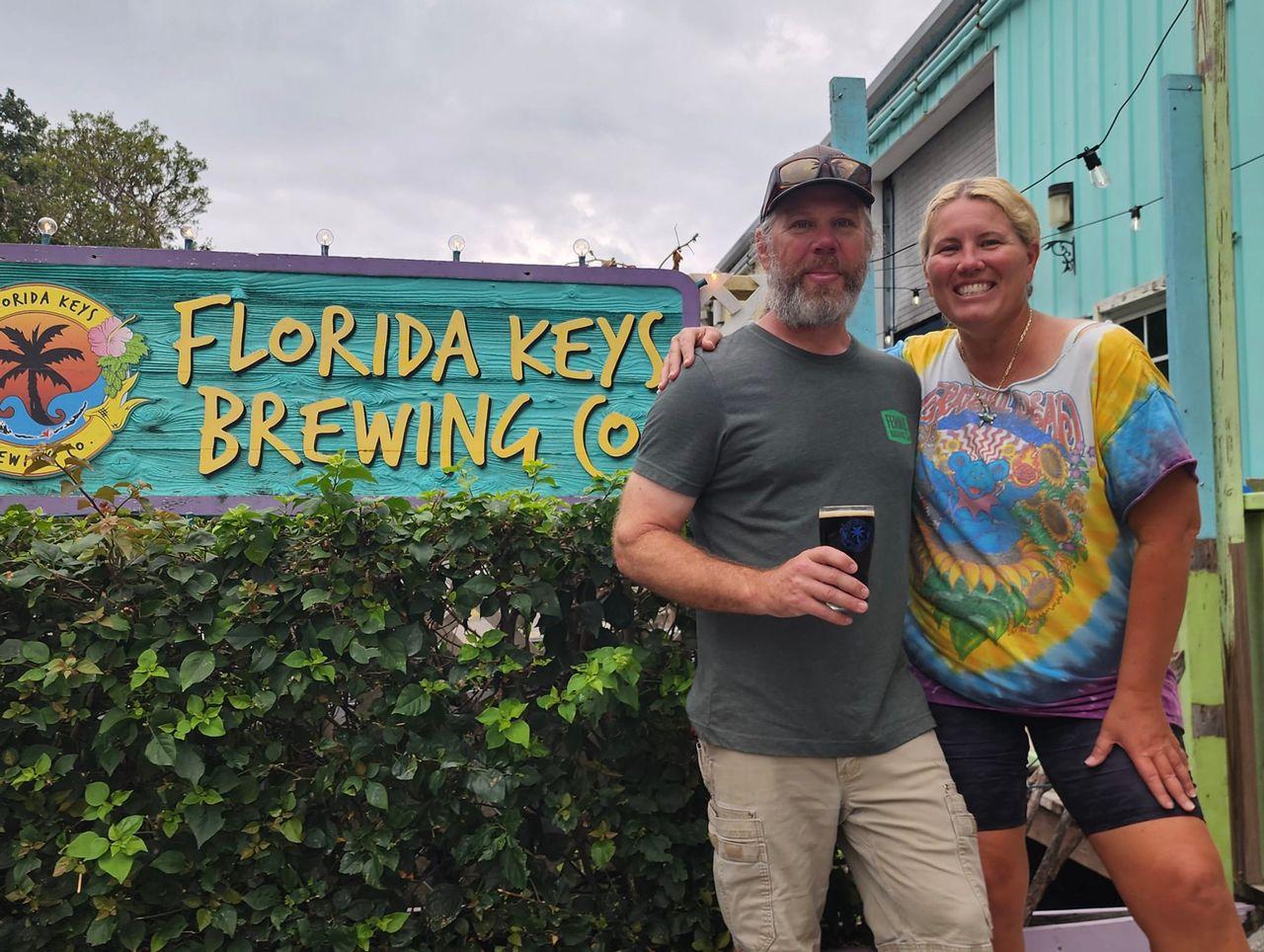 Couple smiling outside Florida Keys Brewing Co, holding a drink.