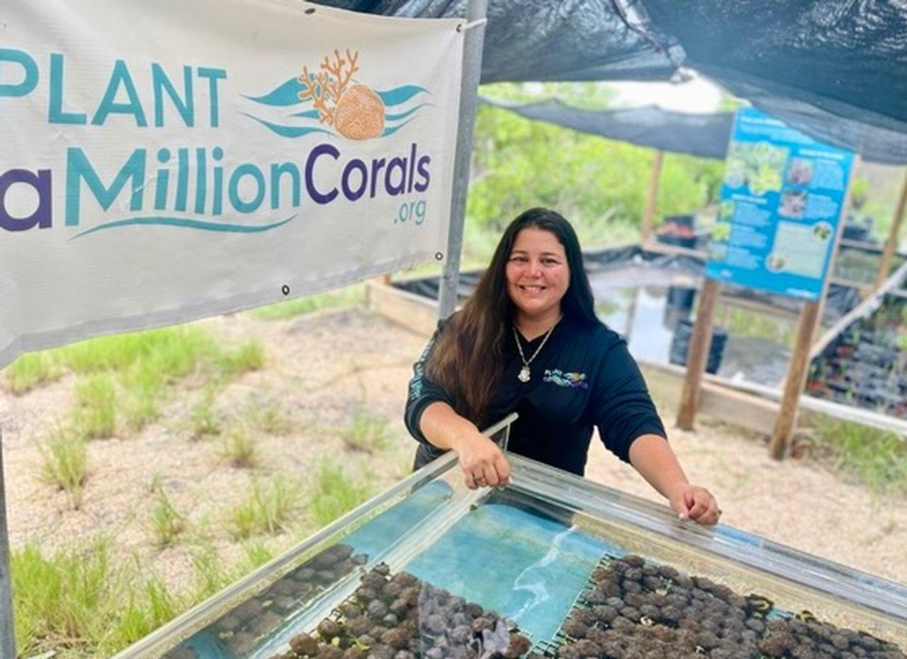Woman smiling at a coral planting station outdoors.