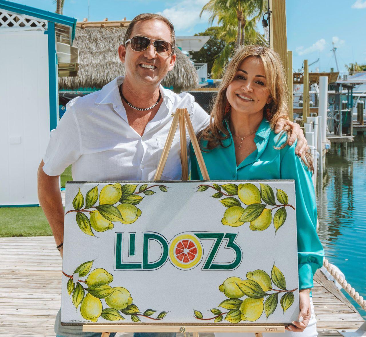 A man and woman outdoors hold a sign with lemons and "LD73" text.