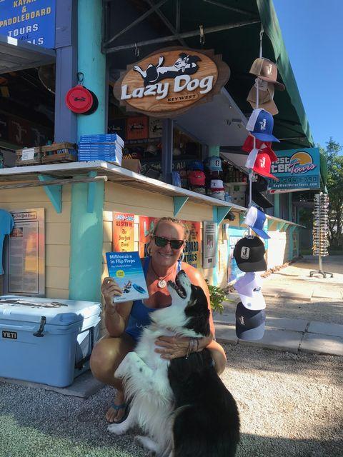 Man with dog outside a shop under a "Lazy Dog" sign.