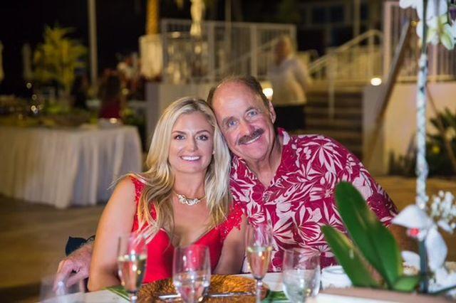 Smiling couple sitting at a dinner table outdoors at night.