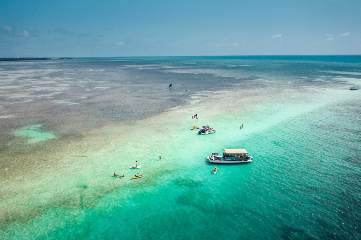 Turquoise ocean with a boat and distant people snorkeling.