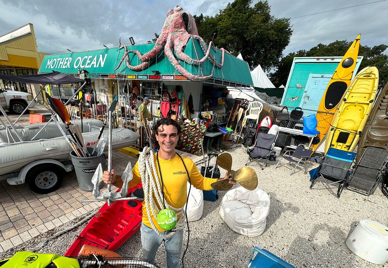 Man smiling in a vibrant outdoor marine shop with an octopus decoration.