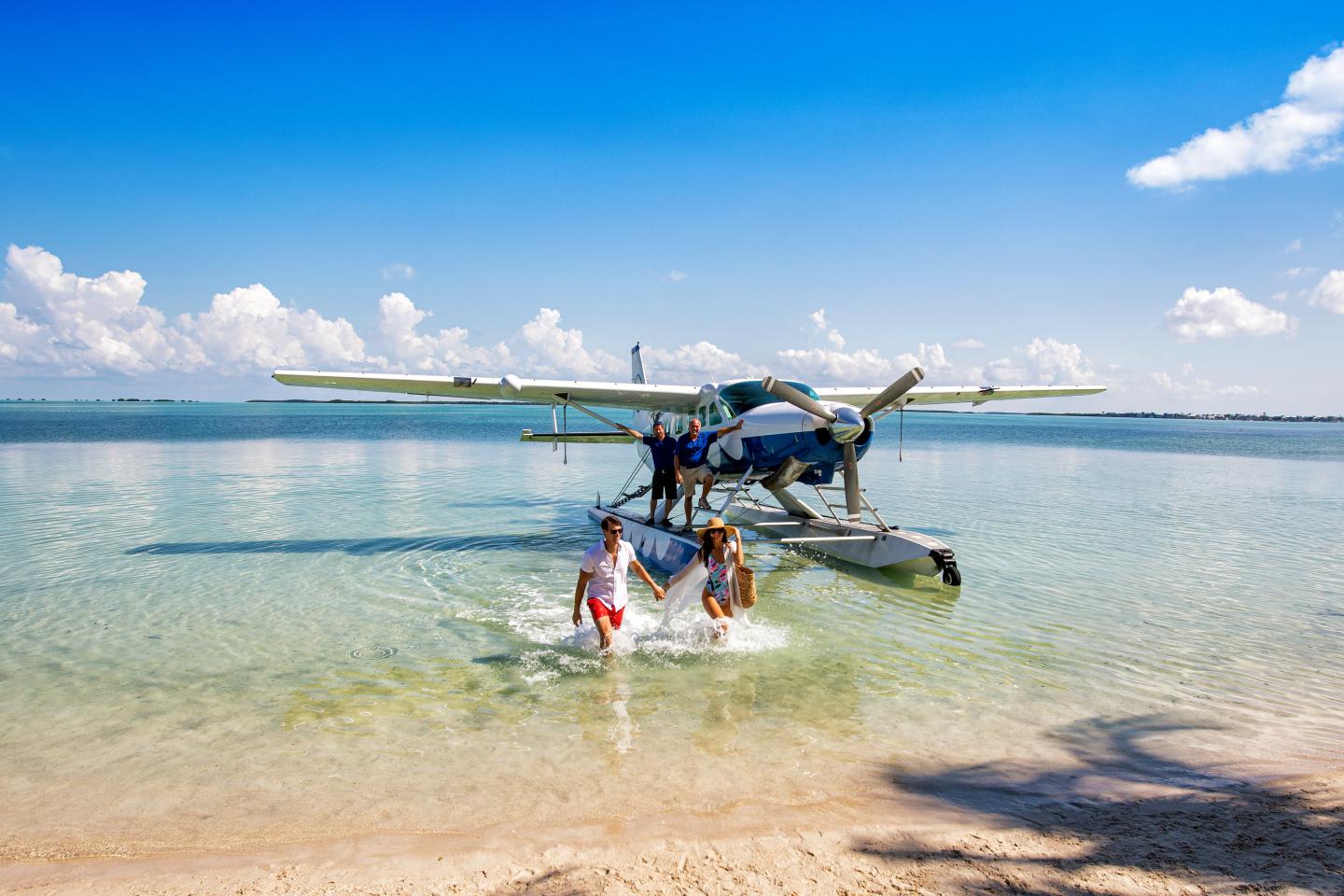 Seaplane near shore with people in water on a sunny day.
