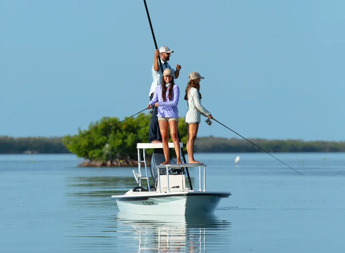 Three people fishing on a boat in calm blue waters, clear sky.