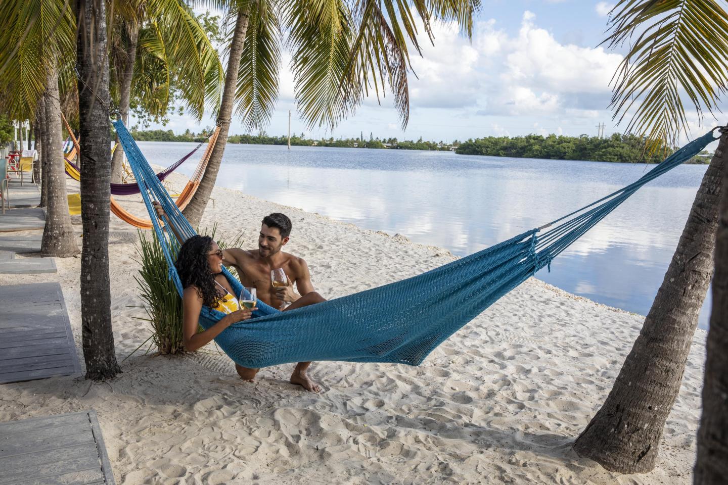Couple relaxing in a hammock on a tropical beach under palm trees.