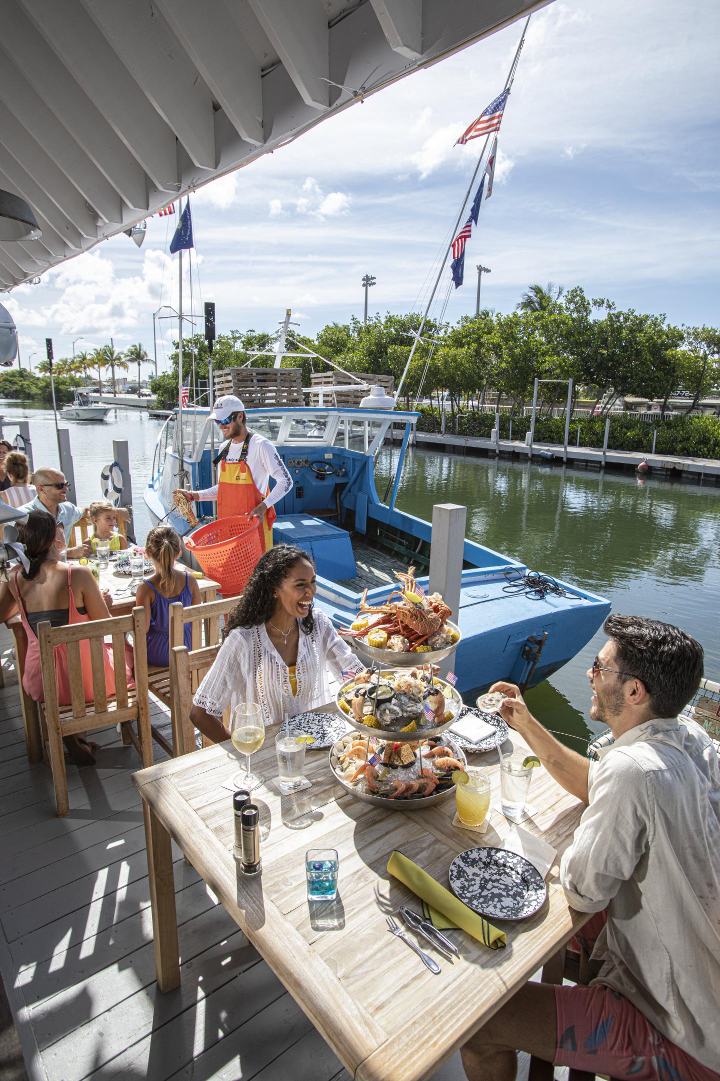 Outdoor dining near a blue boat on a sunny day.