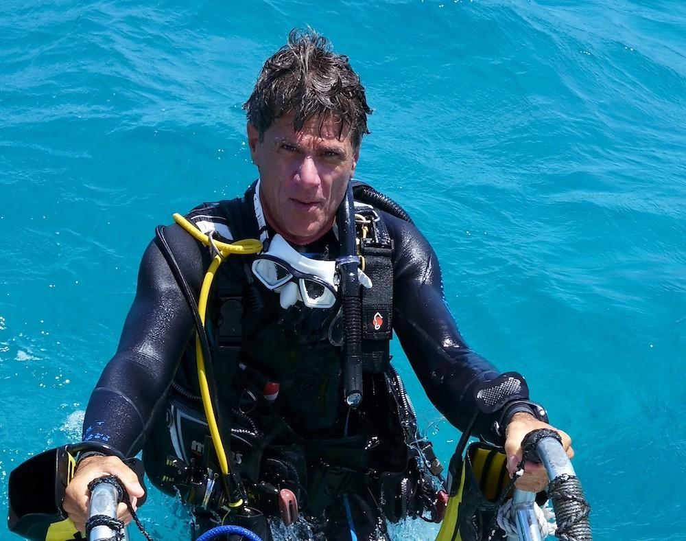 Scuba diver emerging from turquoise water.
