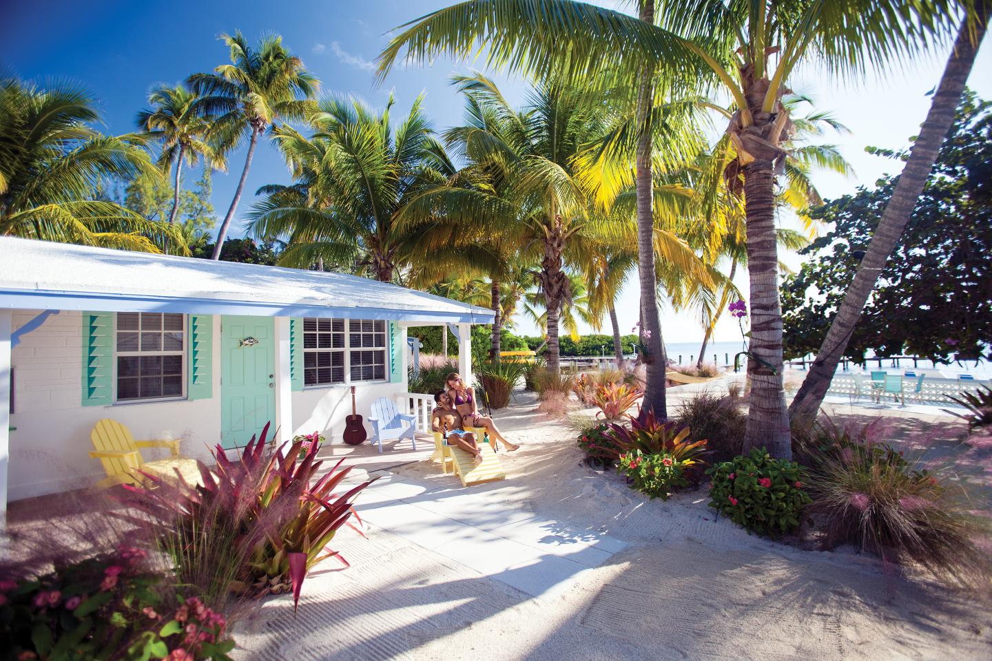Tropical beach house with palm trees and bright blue sky.