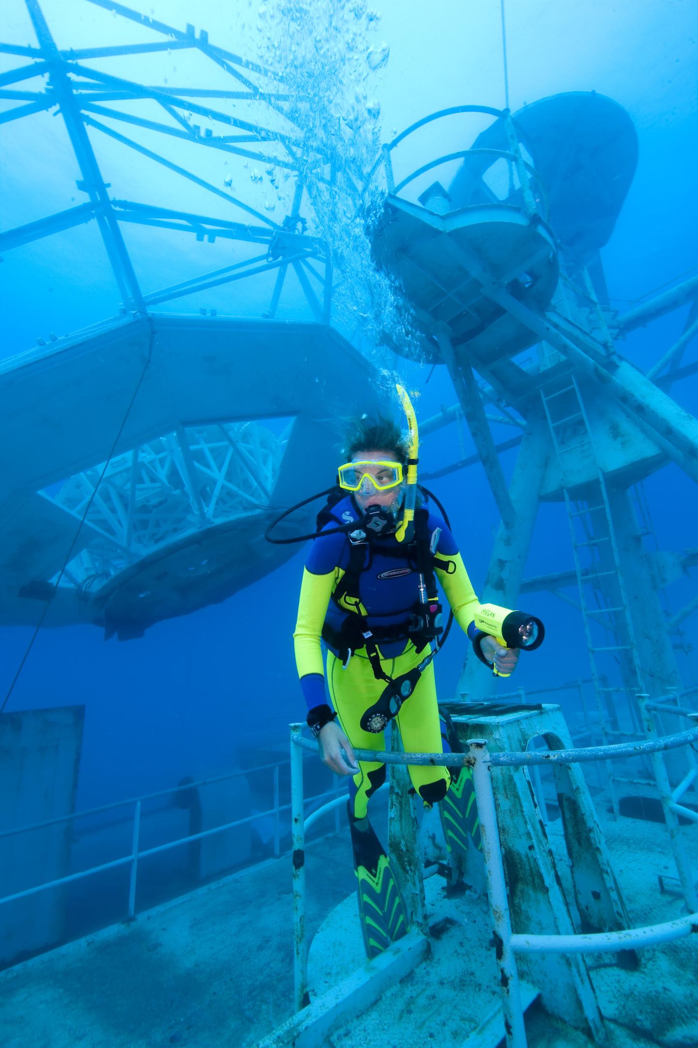 Scuba diver explores underwater structure.