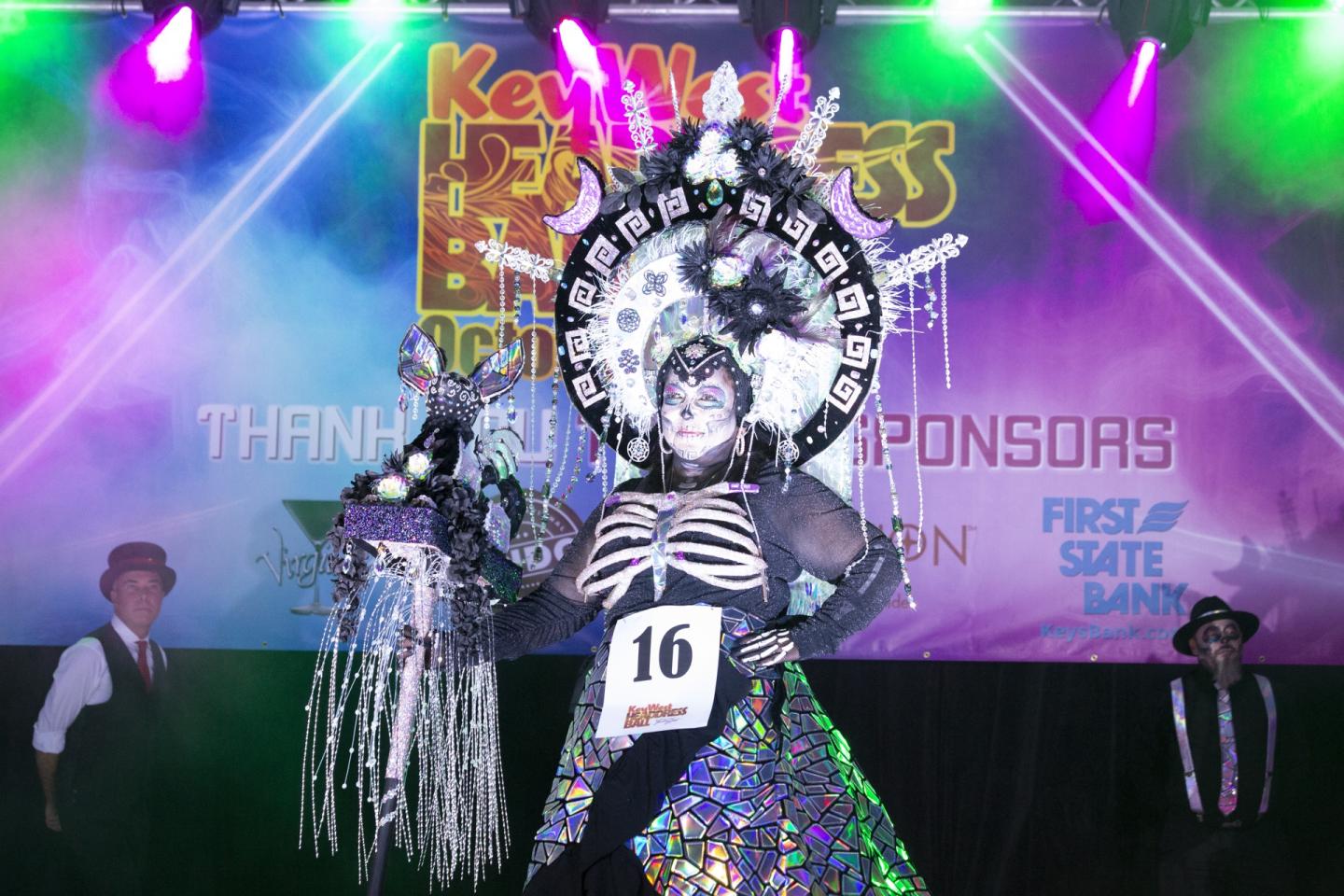 Performer in skeleton-themed costume on a colorful stage.