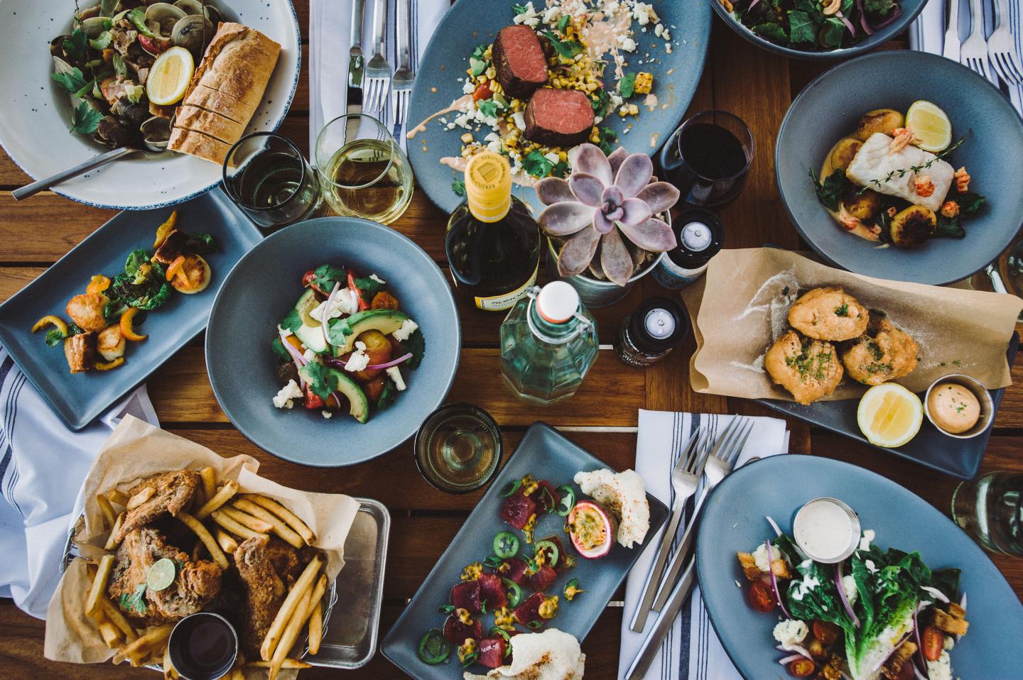 A table with various dishes, including salads, meats, and pastries, on blue plates.