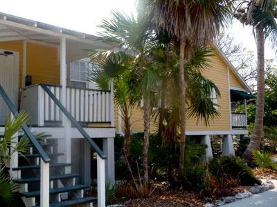 Yellow beach houses with palm trees and a sunny sky.