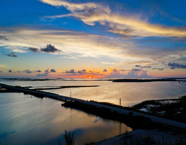 Sunset over a coastal landscape with a long road and vibrant sky.