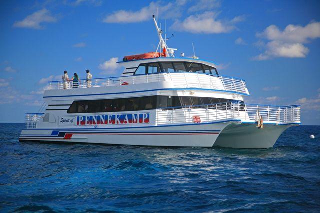 White ferry boat on a sunny sea with a few passengers on deck.