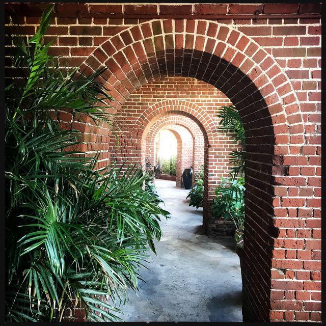 Brick hallway with archways and lush green plants.