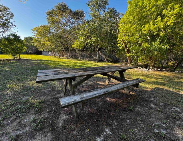 Weathered picnic table in a sunny park with trees.