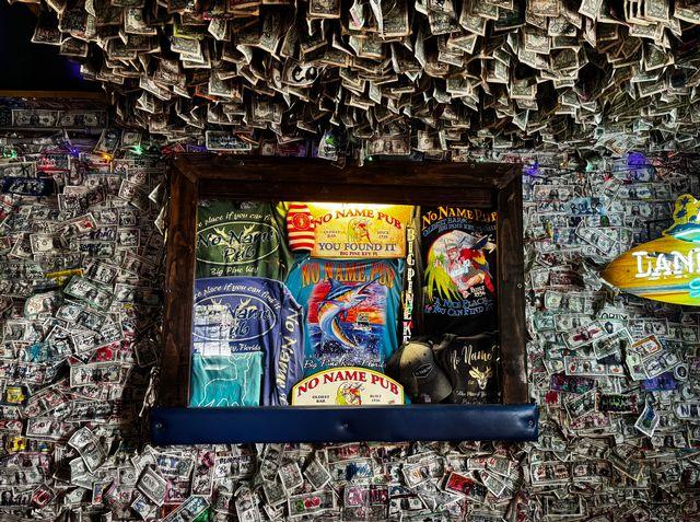 Money-covered walls and ceiling with framed colorful memorabilia.