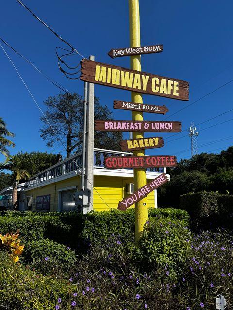 Cafe signpost with directions under a clear blue sky.