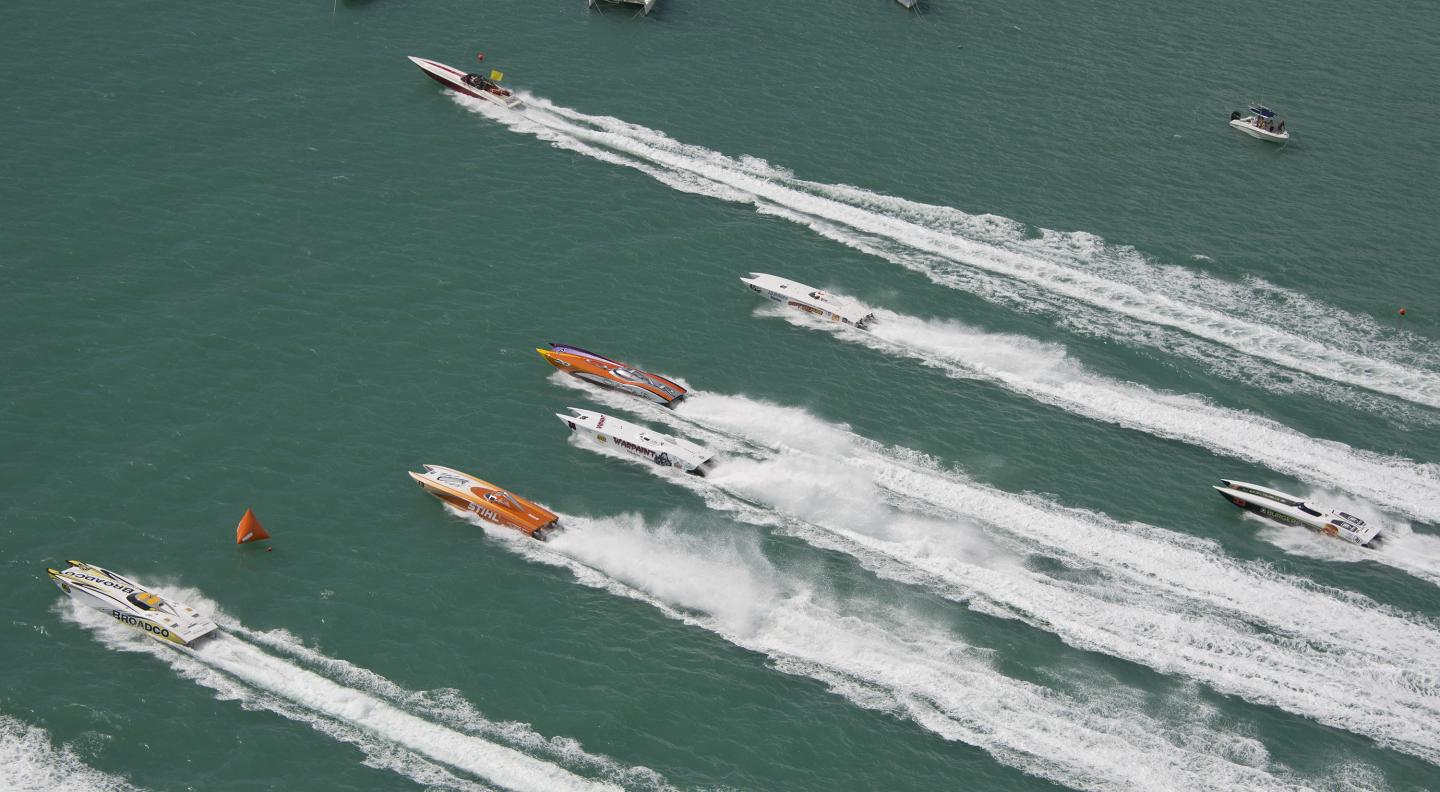 Powerboats racing on open water, leaving white wake trails.