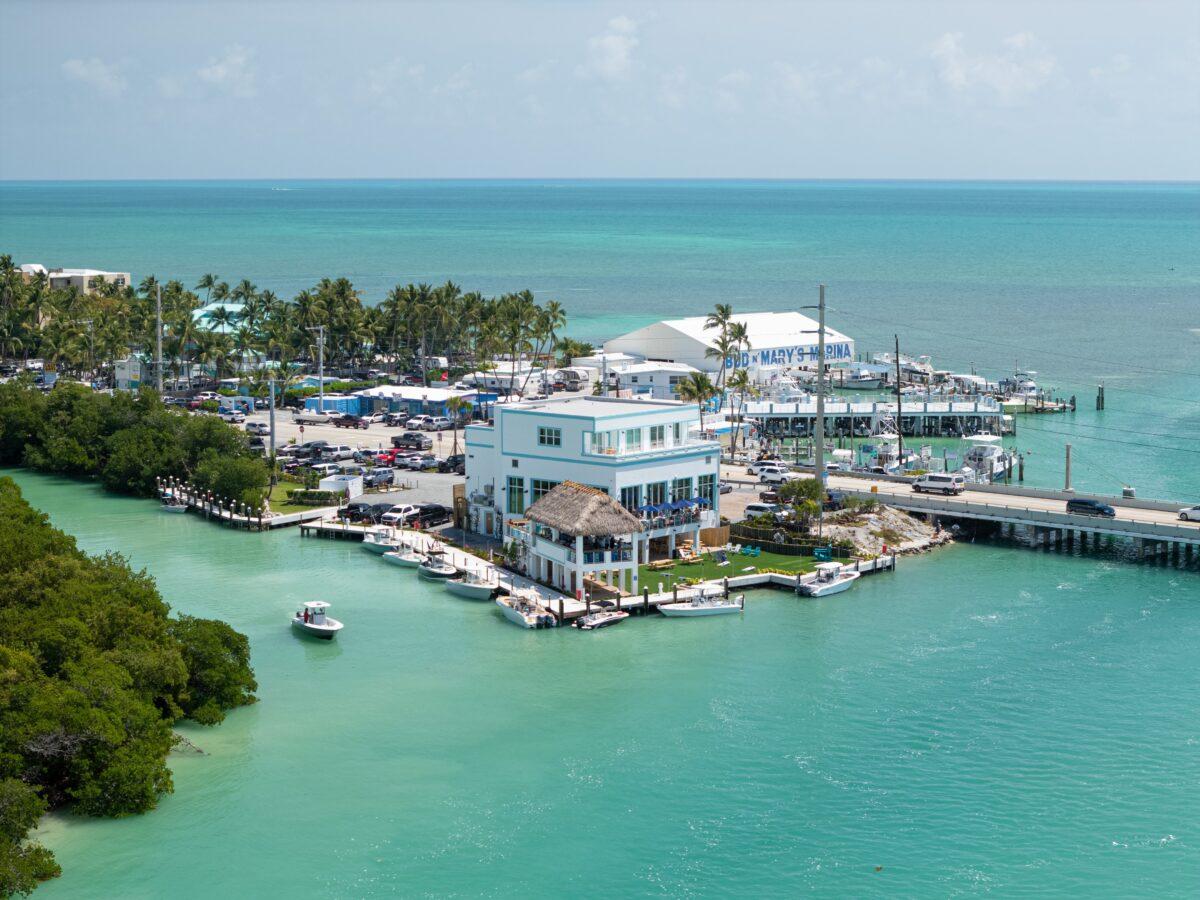 Aerial view of a coastal marina with turquoise water and white buildings.