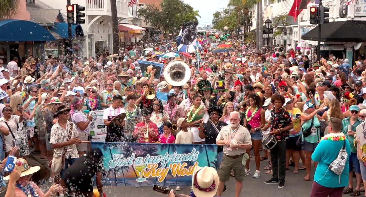 Crowd celebrating in a lively street parade with colorful outfits and banners.