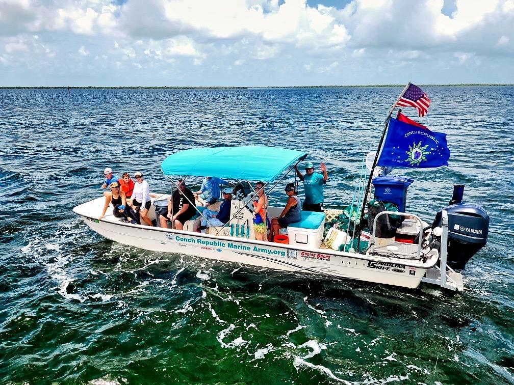 Small motorboat with people, blue canopy, flags waving, on open water.