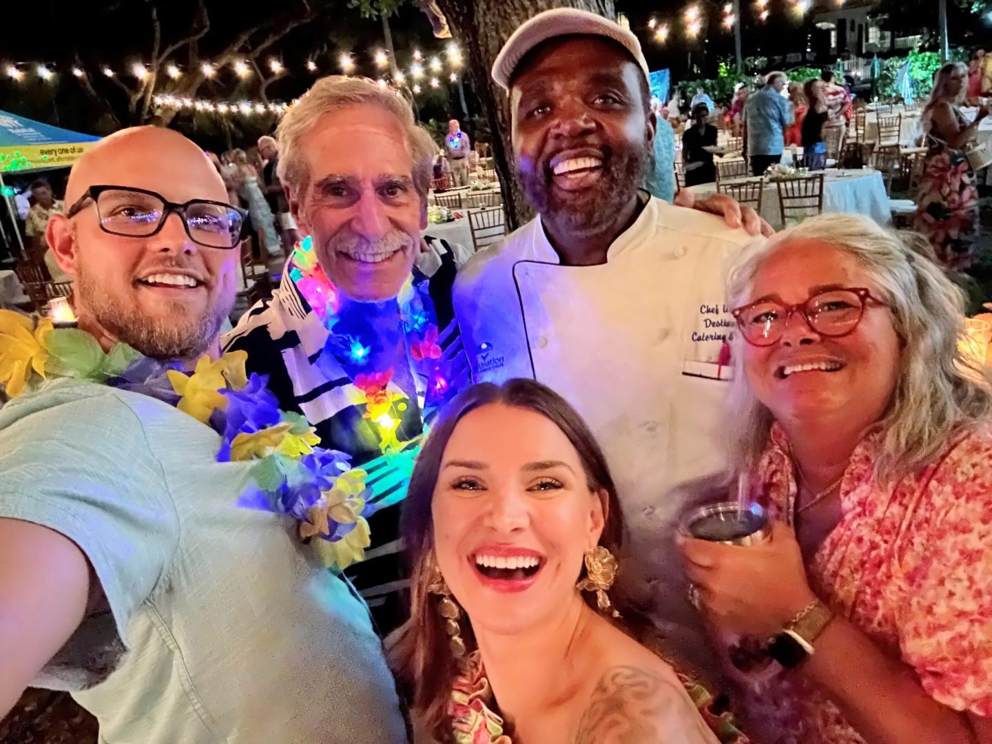 Smiling group at a festive outdoor event with string lights.