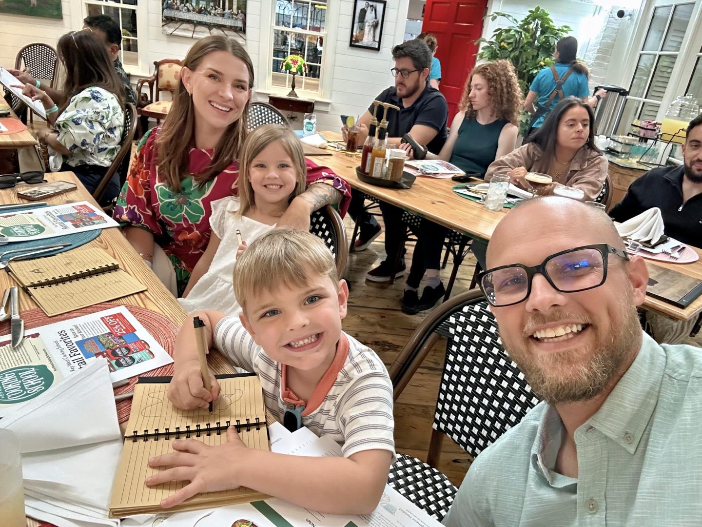 A family of four smiling at a restaurant table.
