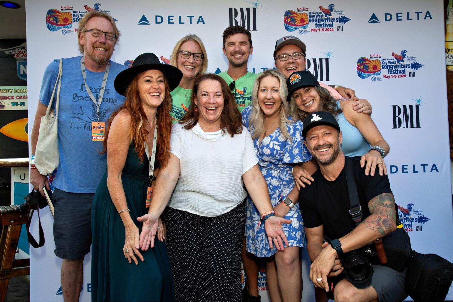 Group of smiling people posing in front of a backdrop with logos.