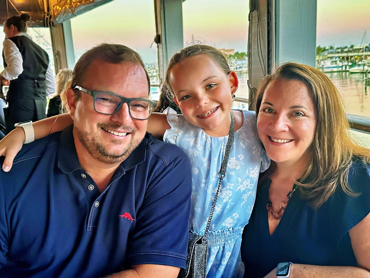 Smiling family at a restaurant with a waterfront view.