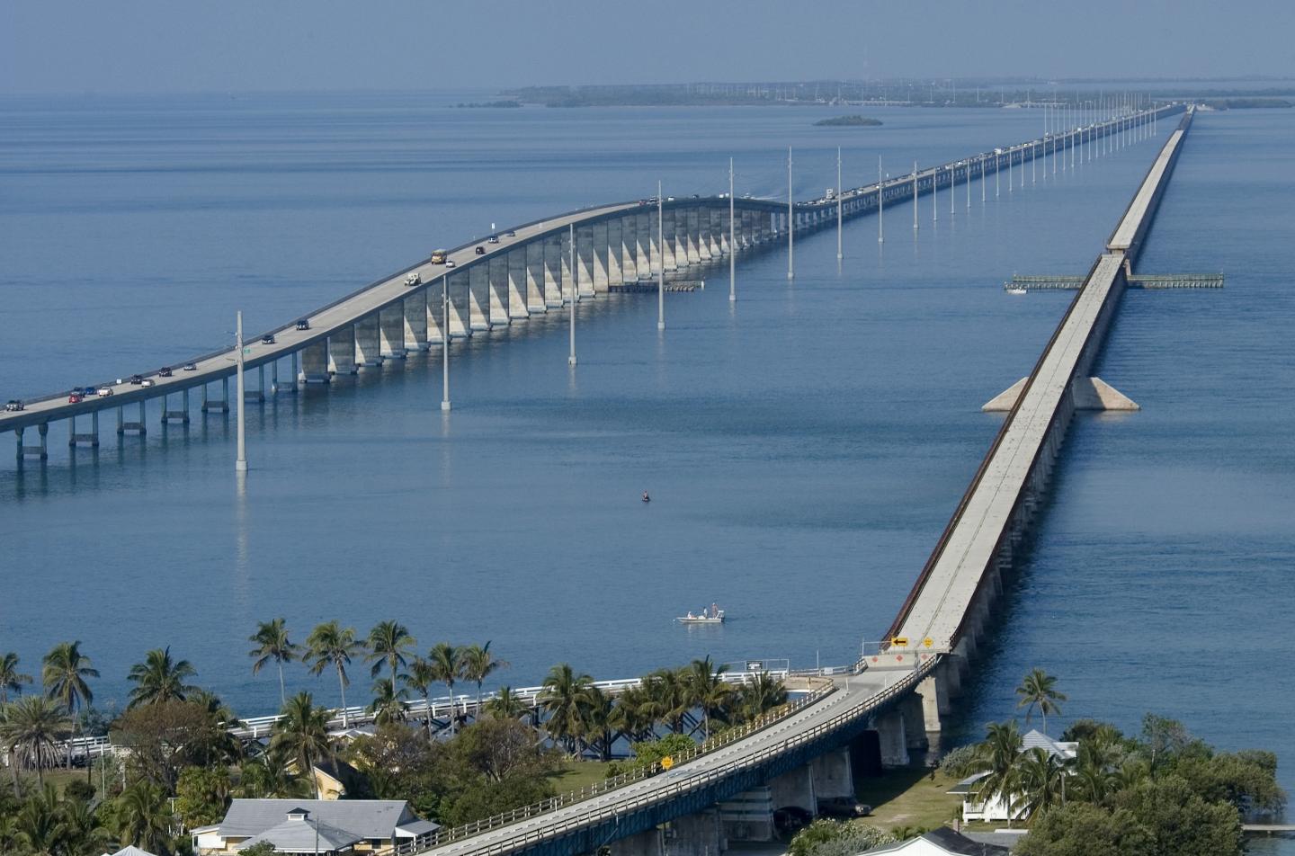 Aerial view of two parallel bridges stretching over calm blue water.