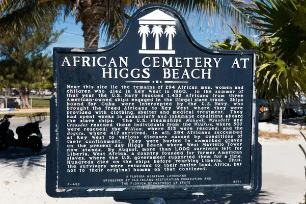 Historical marker for African Cemetery at Higgs Beach under palm trees.