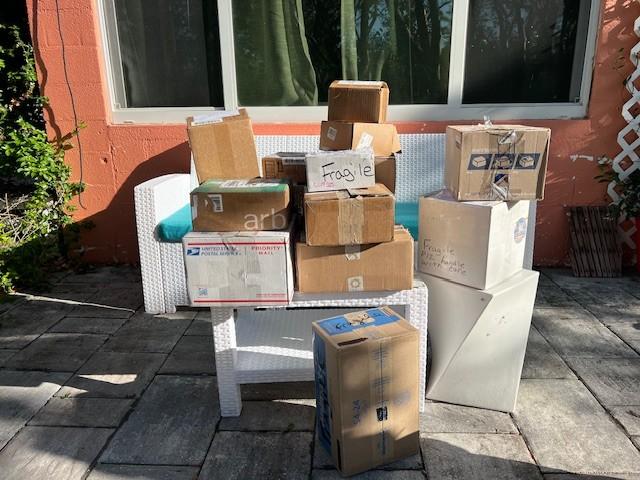 Boxes stacked on a patio chair in sunlight, with a brick wall in the background.