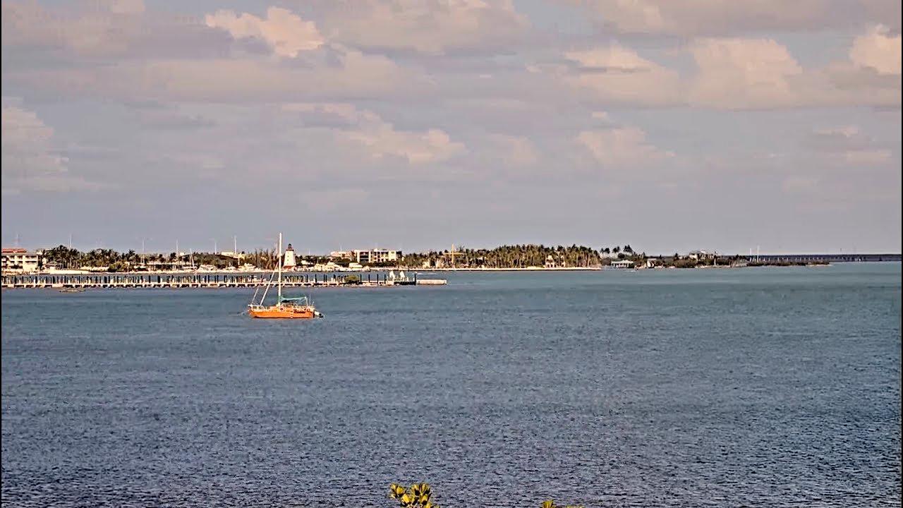 Calm sea with a distant shoreline and a small orange boat.