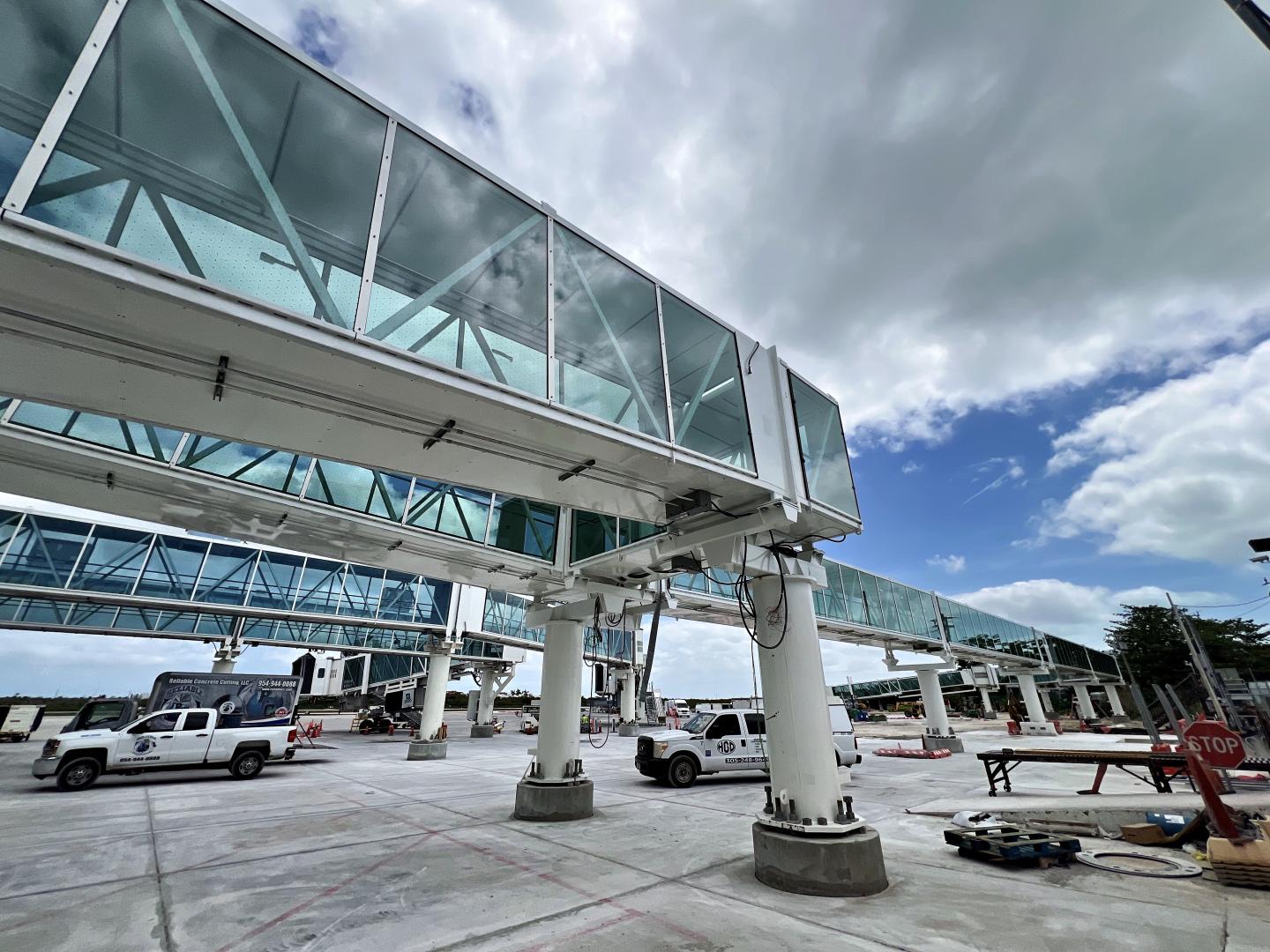 Glass skywalk with trucks beneath, cloudy sky.