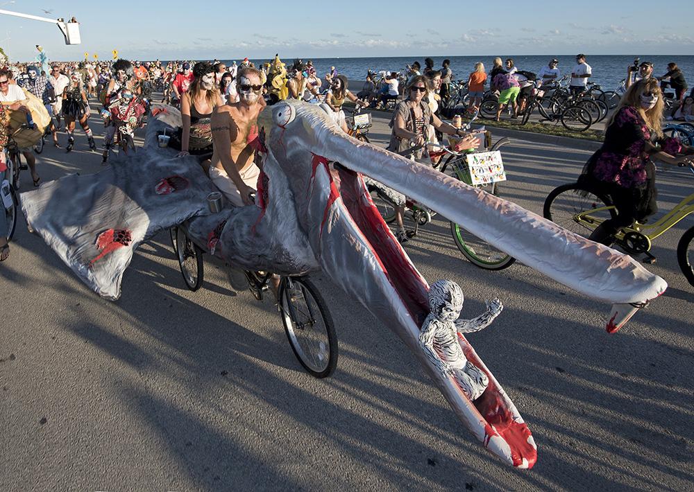 Cyclist in a large pelican costume rides along a road with a group of bikers.
