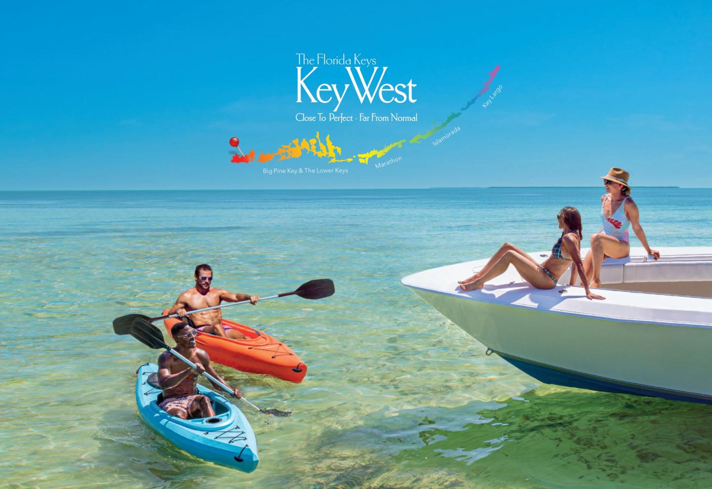 Two people kayaking near a boat, with a couple lounging on it, in clear turquoise waters.