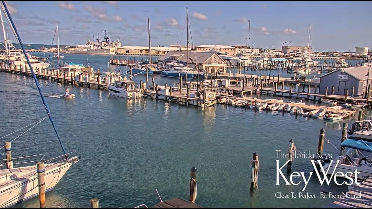 Marina with boats docked, calm water, and clear sky at sunset.