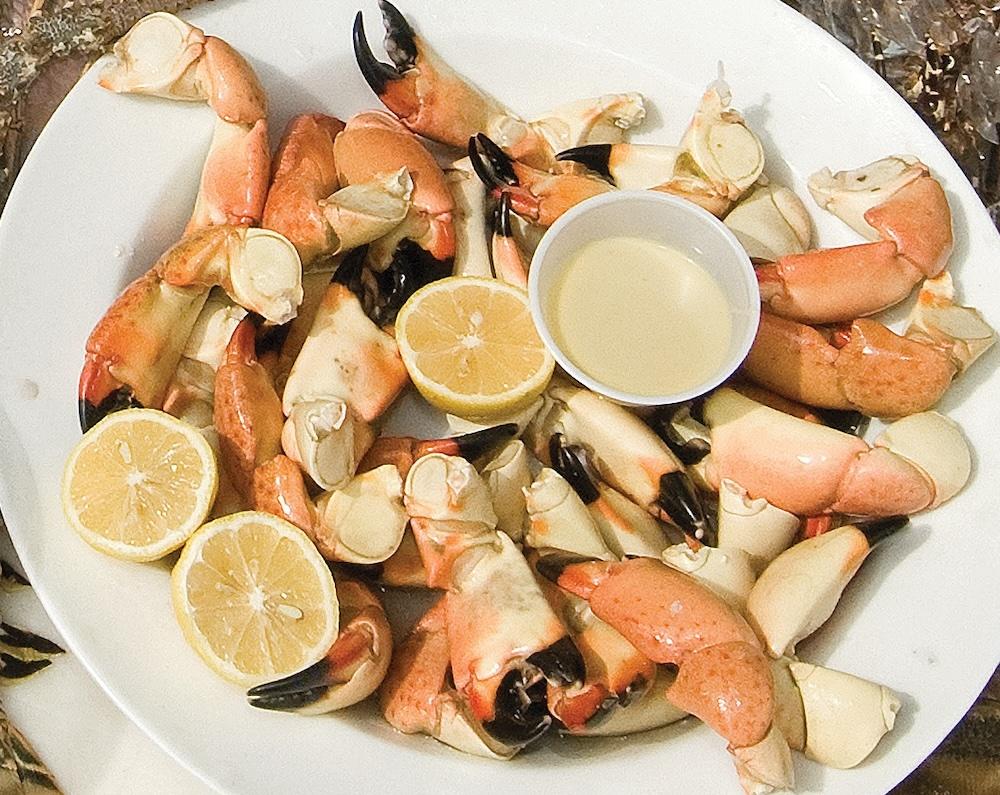 Crab claws on a plate with lemon slices and dipping sauce.