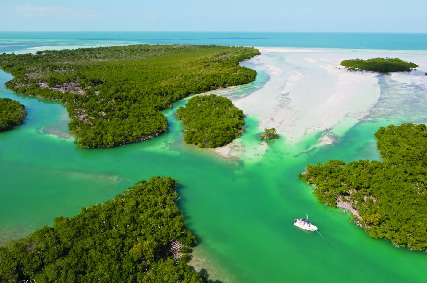 Tropical islands with lush greenery and turquoise water, small boat visible.
